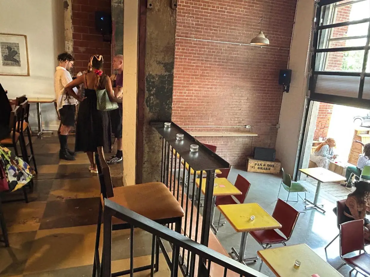 Guests talking on the mezzanine, looking down on the café floor and patio