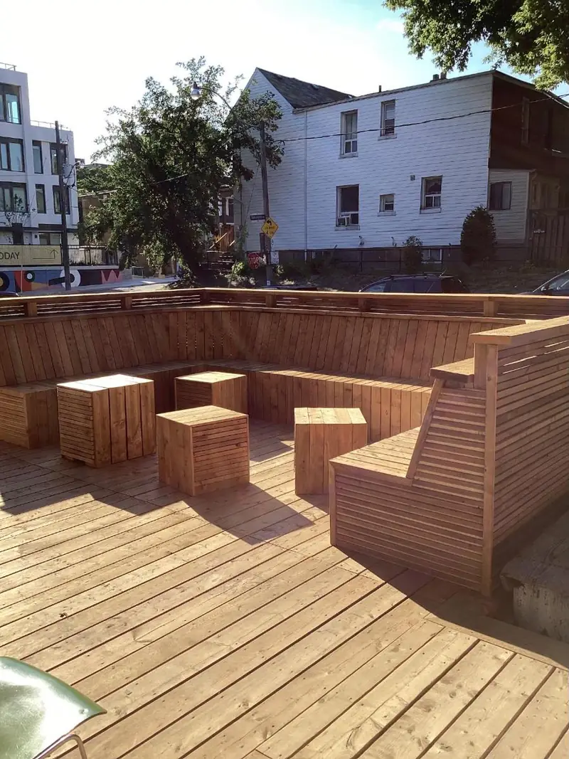 The cedar patio with built-in benches and cube tables in evening sun