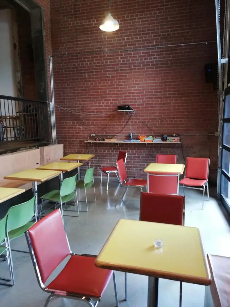 Red chairs and yellow tables against the brick wall
